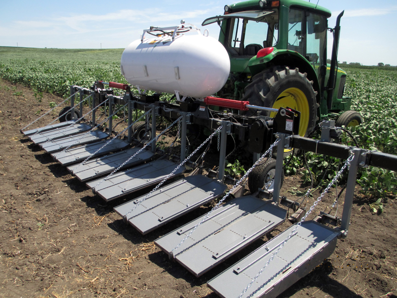 Tractor pulling 8-row flamer in field.