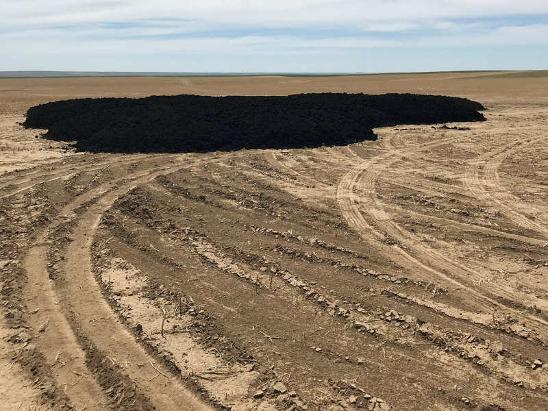 empty field of soil with large pile of biosolids waiting to be spread