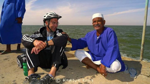 Bike rider talking with Sudanese man at Lake Nassar.