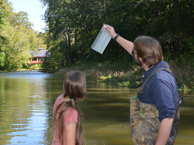 Researcher holds up stream water sample