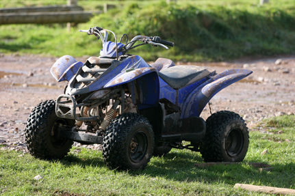 ATV at edge of a dirt trail with tall grass in the background